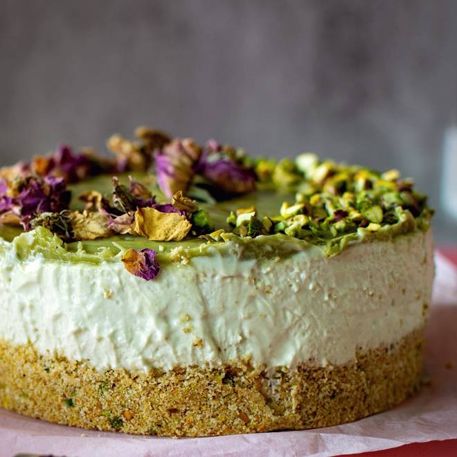 A pistachio cake with a pistachio-crumb base, pale green top and dried rose petals.